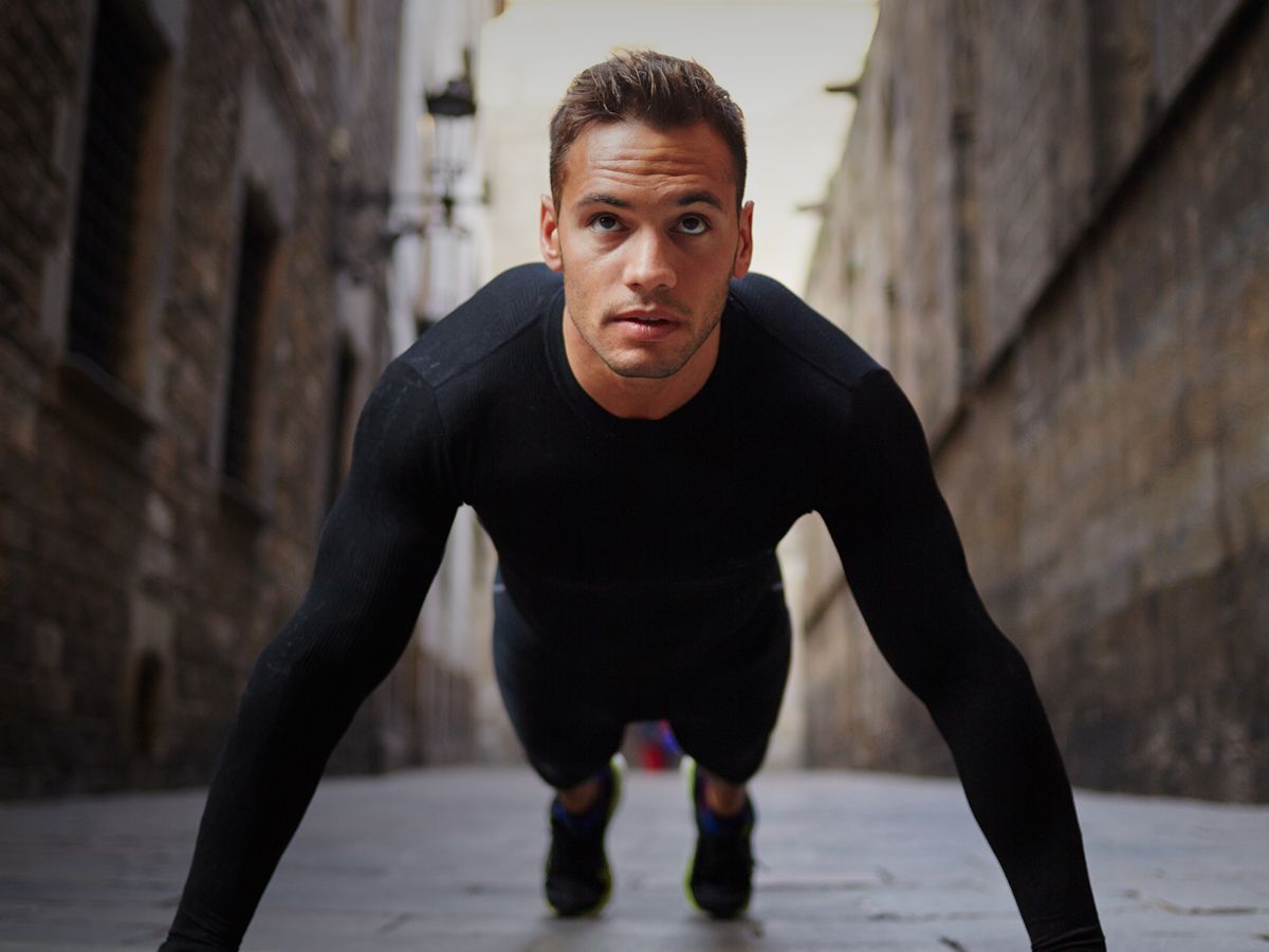 HBOT model doing push-ups in urban alleyway.
